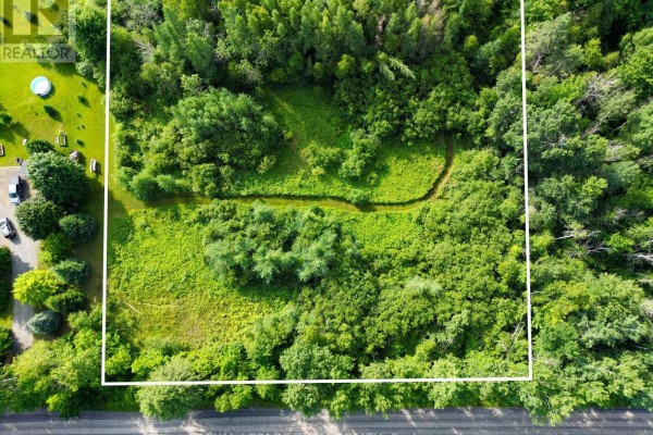 Overhead drone view of a large, green, wooded lot with a meandering stream. - 2630 Mcmullen Road, Ottawa