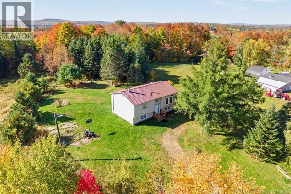 Aerial view of a beige house with a red metal roof situated on a grassy lot with surrounding trees. - 2631 Route 104, Middle Hainesville