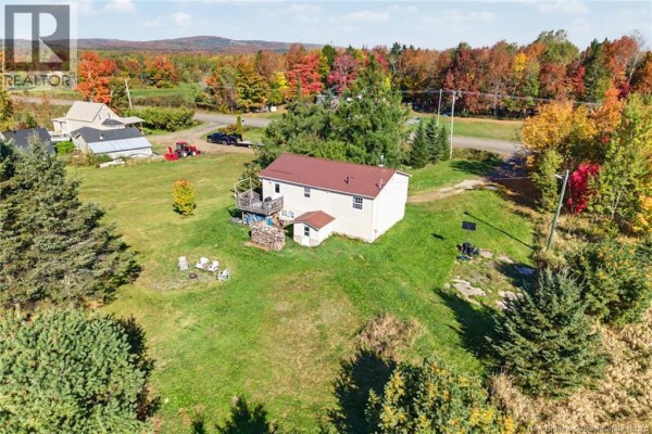Aerial view of the back of a beige house with a red metal roof, showing a deck and surrounding outbuildings. - 2631 Route 104, Middle Hainesville
