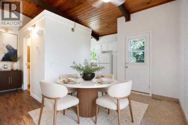 Dining area with a round table, four chairs, and a view into the kitchen and hallway. - 2634 Oakmoor Drive Sw, Calgary