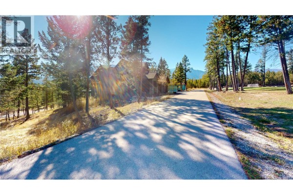 Asphalt road through a wooded area with houses and distant mountains. - 2636 Brewer Ridge Rise, Invermere