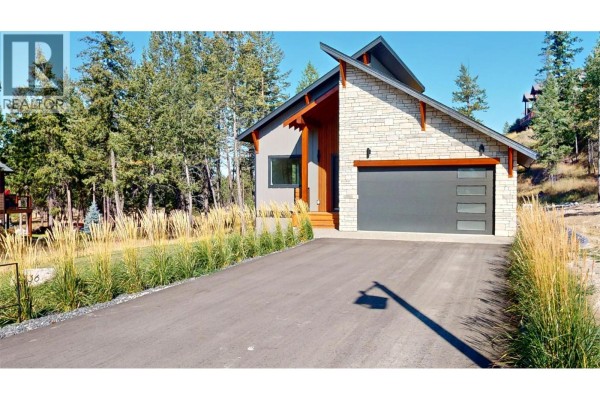 Close-up of the front entrance with wood planks, glass-paneled door, and stone garage detail. - 2636 Taynton Trail, Invermere