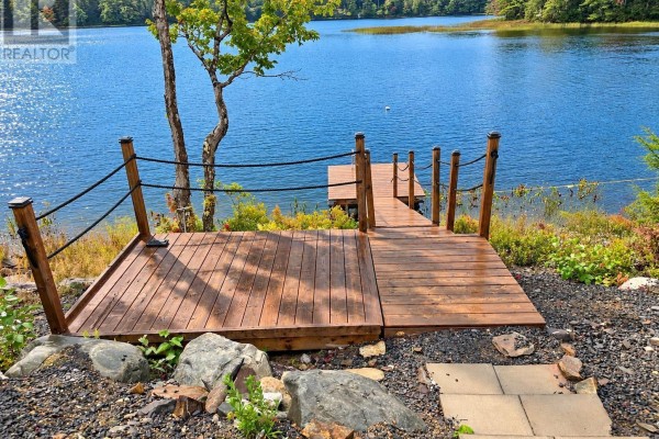 Wooden dock with rope railings extends from a rocky shore into a wide blue lake. - 264 Beaver Dam Trail, Labelle