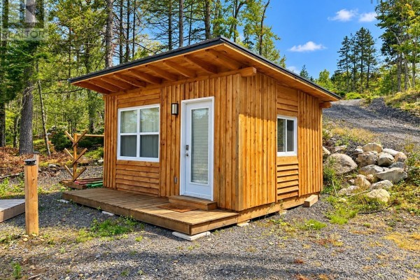 Small wooden cabin with a white door and windows sits on a gravel lot with a wooden porch. - 264 Beaver Dam Trail, Labelle