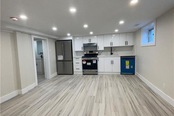 Spacious living area and kitchen with white cabinetry, stainless steel appliances, and light wood-look flooring. - 264 Thayer Avenue Unit# Lower, Hamilton
