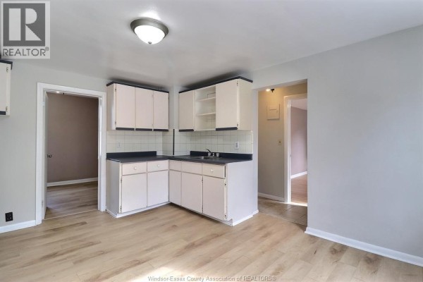 Kitchen area with white cabinets, dark countertops, and light wood-look flooring. - 2640 Whelpton, Windsor