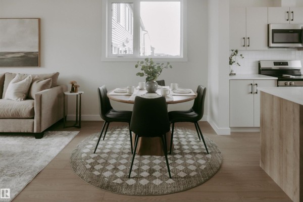 Living and dining area with neutral furniture, hardwood floors, and large windows. - 2641 Alces Wy Sw, Edmonton