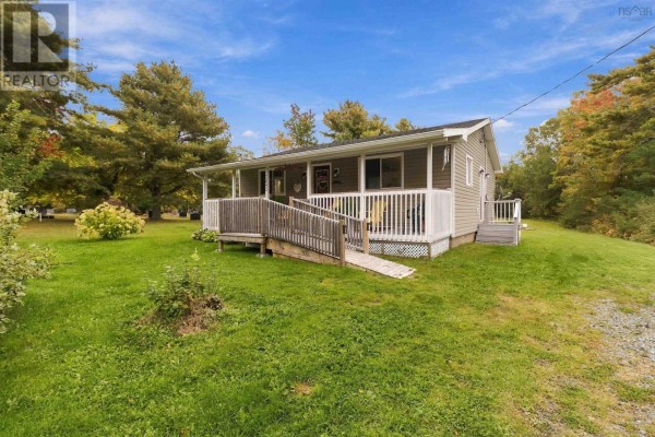 Front view of a single-story grey house with a covered porch and a wooden ramp. - 2643 Highway 210, Chelsea