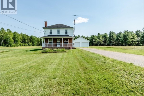 Front view of a white house with a covered porch and a detached two-car garage during winter. - 2649 Saint-ignace, Saint Ignace