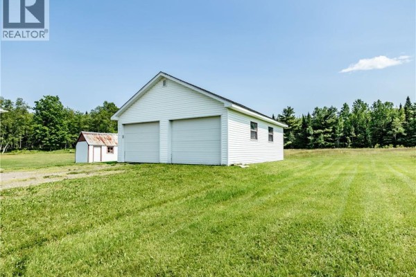 Side view of a detached white two-car garage with two garage doors and a gravel driveway. - 2649 Saint-ignace, Saint Ignace