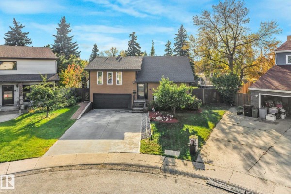 Aerial view of the residential house with a paved driveway, green lawn, and mature trees in the neighborhood. - 265 Grand Meadow Cr Nw, Edmonton