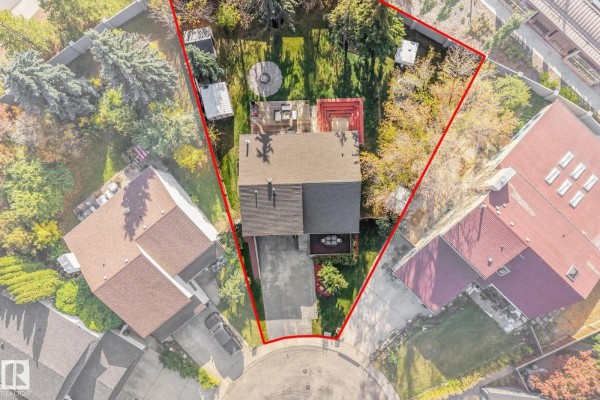 Aerial view of the backyard showing a deck, patio furniture, fire pit, and the property boundary outlined in red. - 265 Grand Meadow Cr Nw, Edmonton