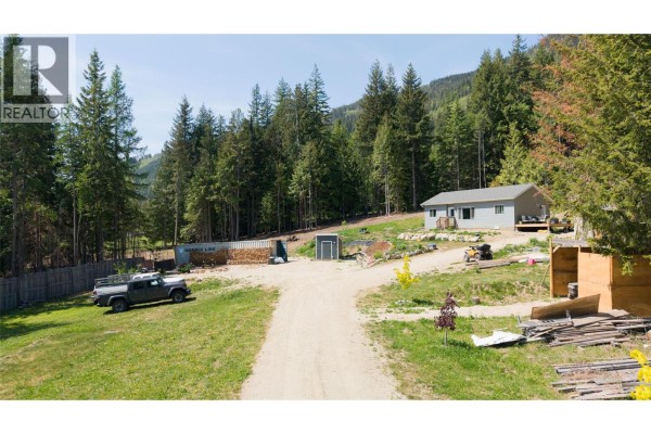 Aerial view of the gray house with a front porch and landscaped stone border. - 2655 Cowan Road, Sicamous