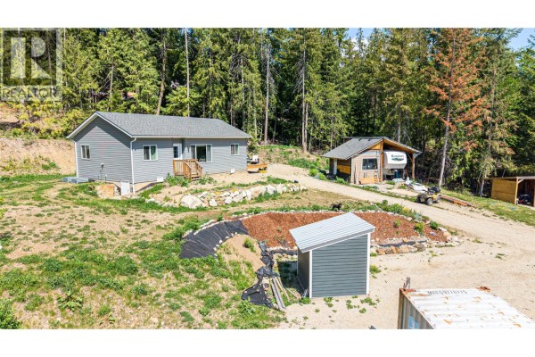 View of the property with a dirt road, trees, and mountains in the background. - 2655 Cowan Road, Sicamous