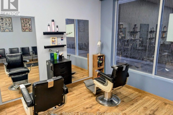 Close-up interior view of the hair salon, showing barber chairs, mirrors, and a large window overlooking the street. - 266 Dundas Street E, Quinte West