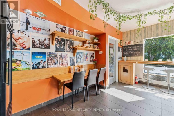 Dining area with posters on orange walls, wooden shelves, and a counter. - 266 Preston Street N, Ottawa
