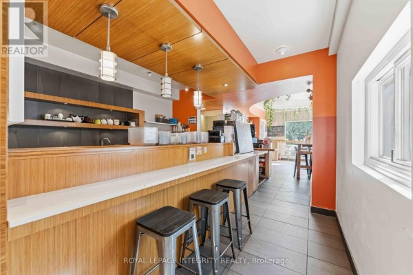 Interior counter area with wooden cabinets, metal stools, and pendant lighting. - 266 Preston Street N, Ottawa