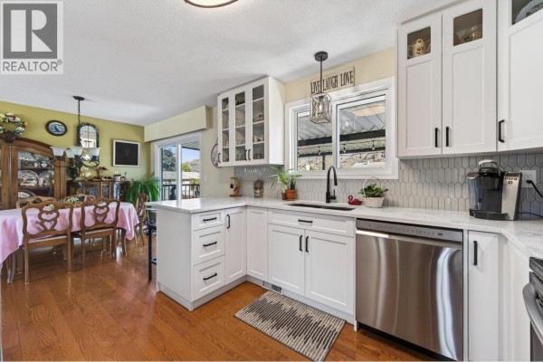 Kitchen with white cabinetry, subway tile backsplash, stainless steel sink, and stainless steel dishwasher. - 2660 Argyle Avenue, Kamloops