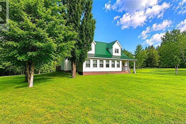 Side view of the white house with a green roof, surrounded by green grass and trees. - 2668 Rte 363, Saint Sauveur