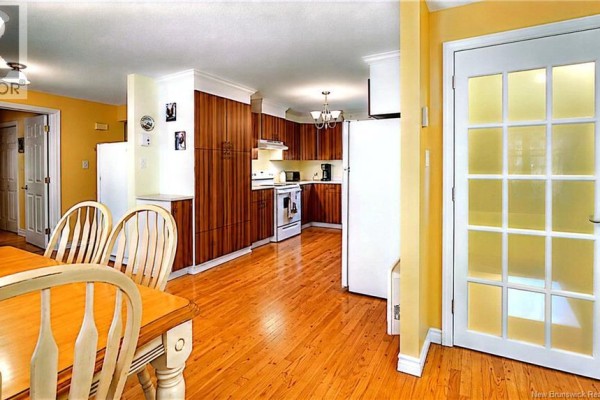 A bright kitchen with honey-colored wood cabinets, white appliances, and a dining table with chairs. - 2668 Rte 363, Saint Sauveur