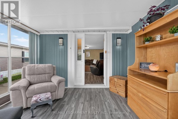 Sunroom with teal paneled walls, recliner chair, and an open doorway to the living room. - 267 - 3033 Townline Road, Fort Erie