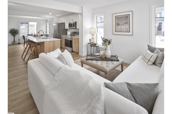 Open concept living and kitchen area with a white sofa and island. - 267 Deer Valley Dr, Leduc