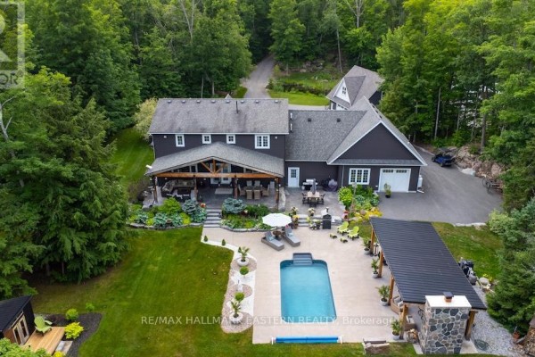 Rear aerial view of the house featuring a large covered patio, swimming pool, and outdoor seating area. - 267 Edwina Drive, Trent Lakes