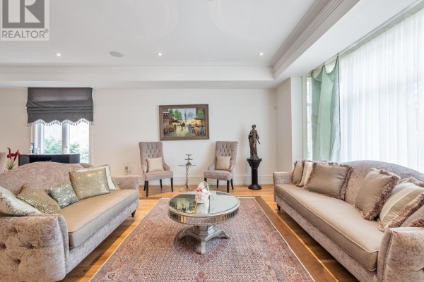 A spacious living room with two sofas, two chairs, a round coffee table, and a large rug. - 267 Empress Avenue, Toronto