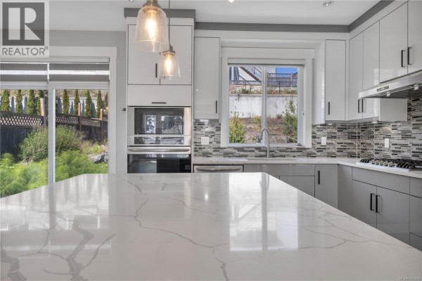 Kitchenette featuring white shaker cabinets, a stainless steel range, and a grey tile backsplash. - 267 Golden Oaks Cres, Nanaimo