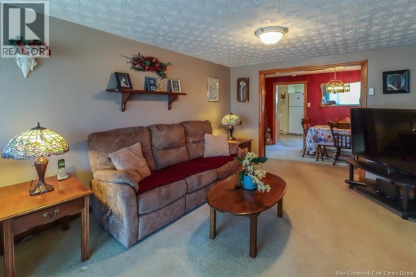Living room with a brown sofa, oval coffee table, two side tables, and a doorway to a dining area. - 267 Milford Road, Saint John