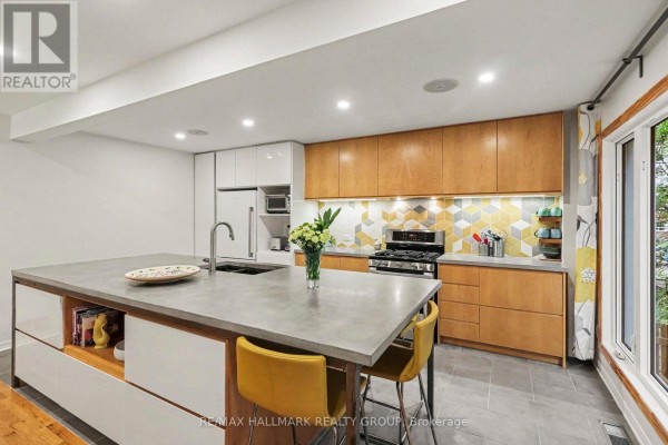 Modern kitchen with a concrete island and view down a hallway with wood floors. - 267 St Laurent Boulevard, Ottawa