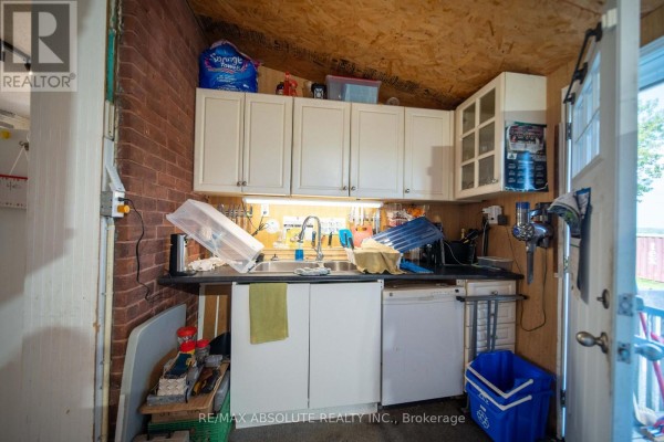 Kitchenette with white cabinets, double sink, dishwasher, and exterior door - 2671 Champlain Street Clarence Rockland