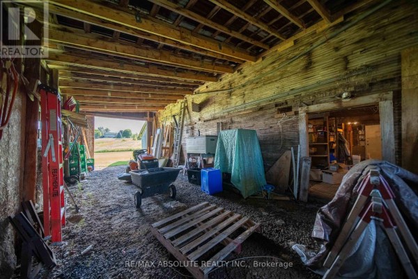 Interior view of a large wooden structure with exposed beams, lawn mower, and storage items - 2671 Champlain Street Clarence Rockland