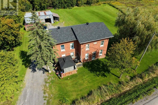 Overhead view of a red brick house, a metal shed, and surrounding green landscape. - 2671 Champlain Street, Clarence Rockland