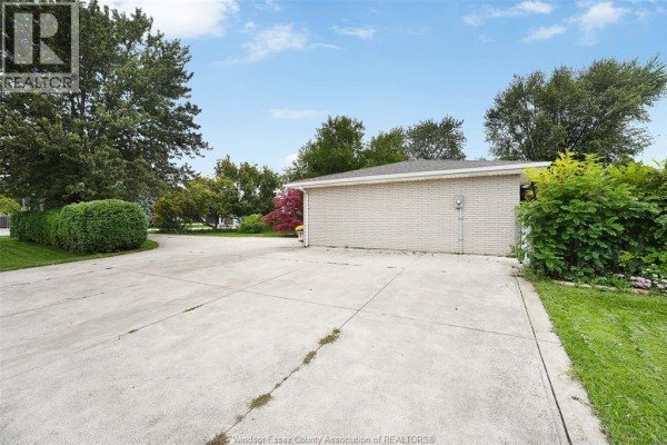 Back view of a brick house with a long concrete driveway, surrounded by green landscaping. - 268 Broadway Street, Belle River