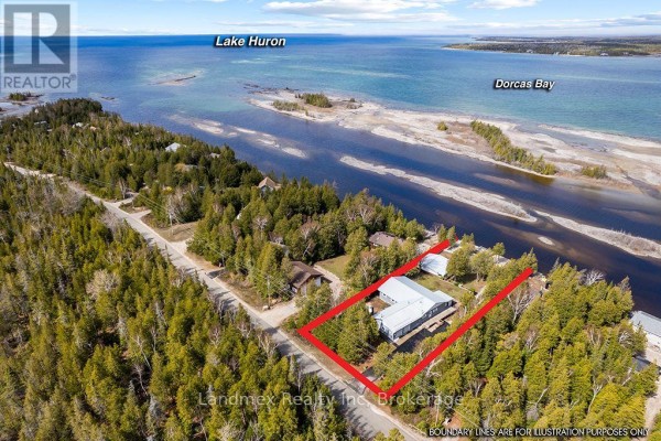 Waterfront view of a white structure, picnic area, and water from a grassy yard. - 268 Dorcas Bay Road, Northern Bruce Peninsula