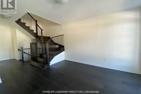 Interior staircase with dark wood treads and black metal railing in an open concept space. - 268 Silk Twist Drive, East Gwillimbury