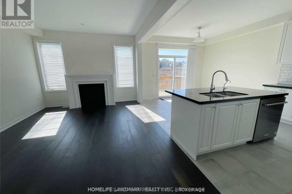 Living room area with white fireplace, dark wood floors, and a kitchen island. - 268 Silk Twist Drive, East Gwillimbury