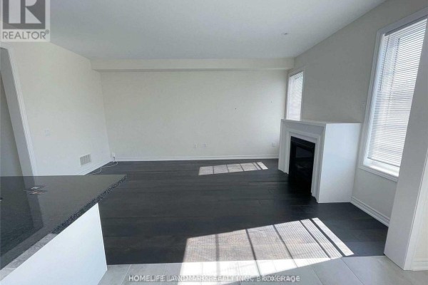 View of a living room with dark floors, white trim, and a fireplace on the right. - 268 Silk Twist Drive, East Gwillimbury