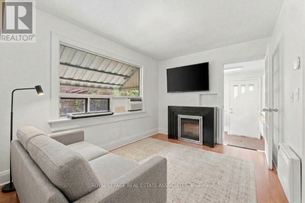 Living room with grey sofa, black fireplace, flat-screen TV, and a large window. - 268 Troy Street, Mississauga
