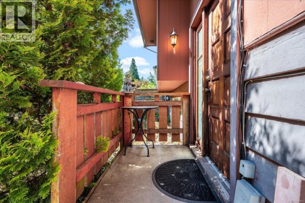 Small covered porch with wooden railing and a table next to the front door. - 2682 Beaver Creek Cres, Nanaimo