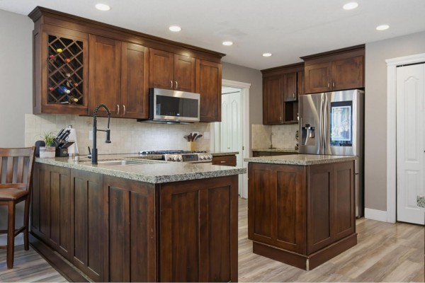 Kitchen and dining area with dark wood cabinets, granite countertops, and a large window overlooking the backyard. - 26860 24a Avenue, Langley