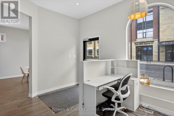 Reception desk with a computer and black office chair facing an arched window. - 269 Charlotte Street, Peterborough