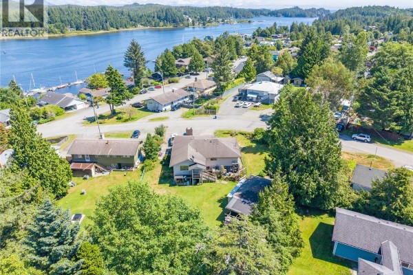 Elevated aerial view showing the house, surrounding trees, and distant water with boats. - 269 Matterson Dr, Ucluelet