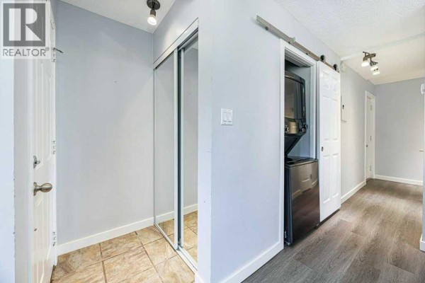 Hallway with stacked washer and dryer, sliding barn door, and mirrored closet. - 27, 11 Stanton Street, Red Deer