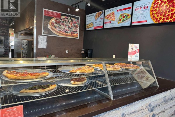 Close-up view of Pizzaville's glass counter displaying pizzas and menu boards on wall. - 27 - 1111 Davis Drive, Newmarket
