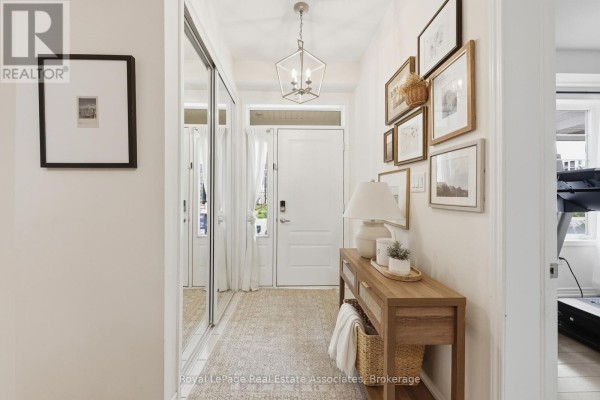 Interior entryway with mirrored closet doors, a white door, and a wooden console table with art. - 27 - 1222 Rose Way, Milton