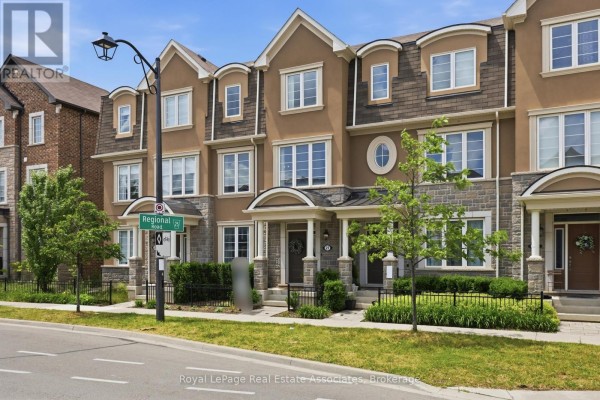 Street view of townhouses with stone and stucco facades and dormer windows on a sunny day. - 27 - 1222 Rose Way, Milton