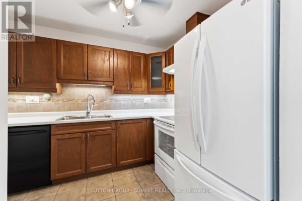 Kitchen showing white refrigerator, dark wood cabinets, and white appliances. - 27 - 1396 Upper Ottawa Street, Hamilton