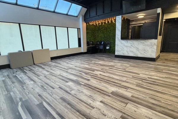 Commercial space with wood-look flooring, large windows with blinds, and tables stacked against the wall. - 27 - 501 Passmore Avenue, Toronto
